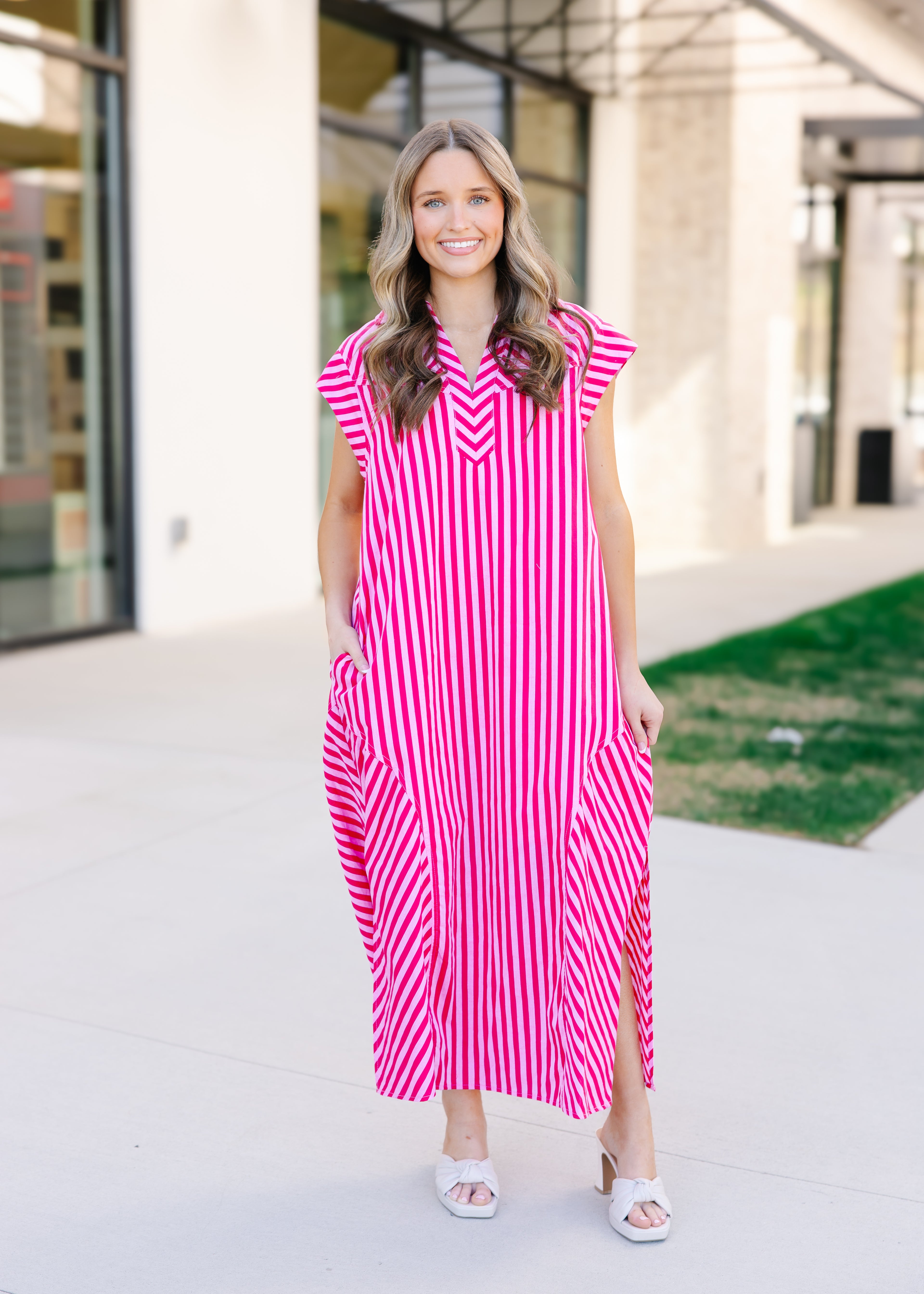 Woman wearing a pink and white striped dress standing outdoors.