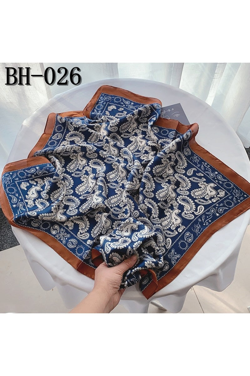 Blue and brown patterned handkerchief held by a hand on a white surface with a blurred background.
