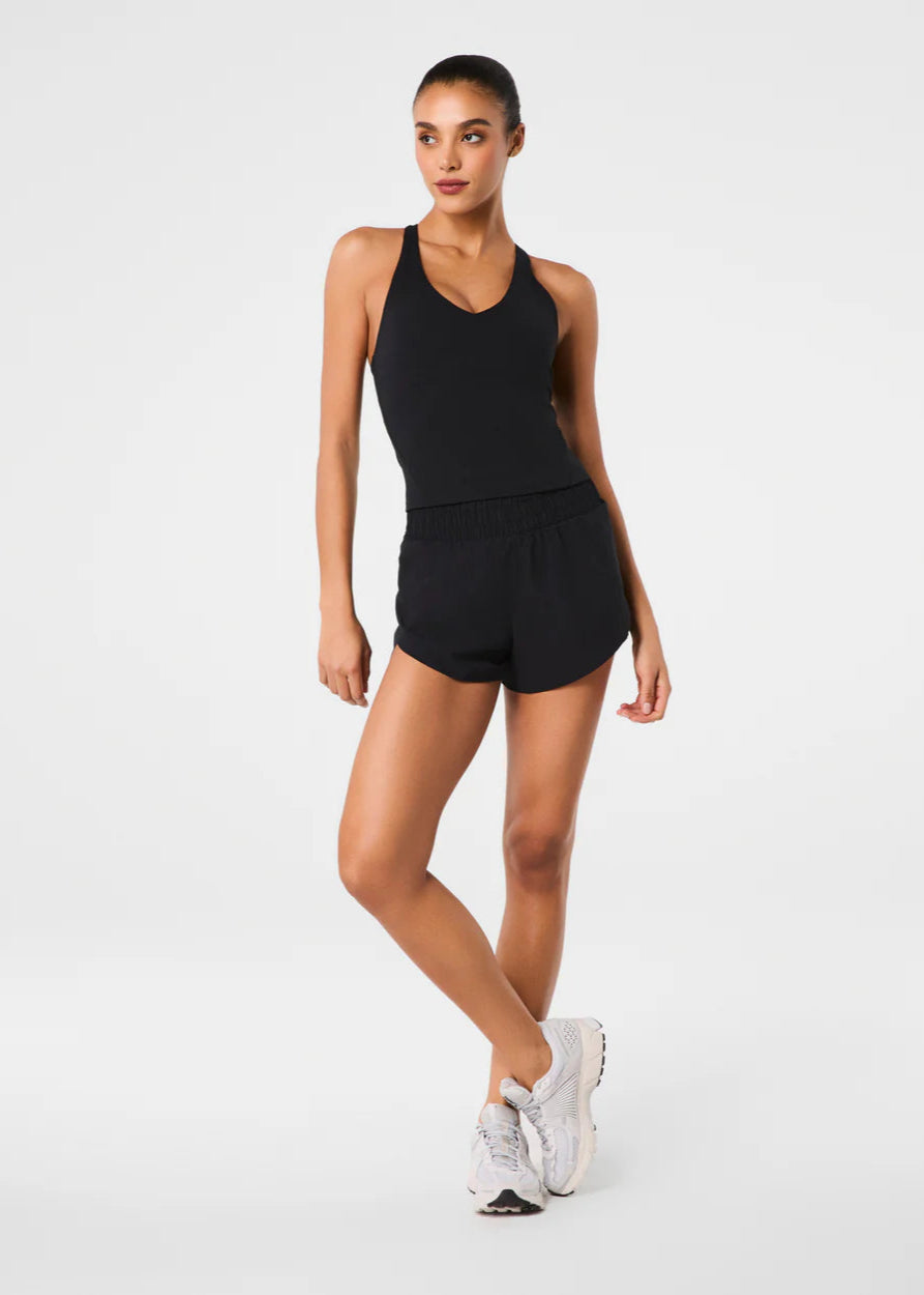 Woman wearing a black tank top and shorts on a white background