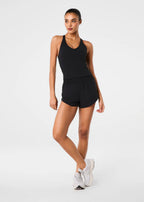 Woman wearing a black tank top and shorts on a white background