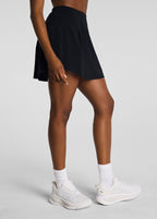 Person wearing a black skirt and white sneakers on a light gray background