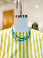 Necklace on a mannequin with a striped dress in a store setting