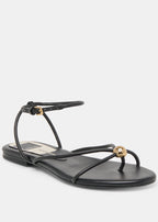 Black sandal with thin straps and gold accents on a white background