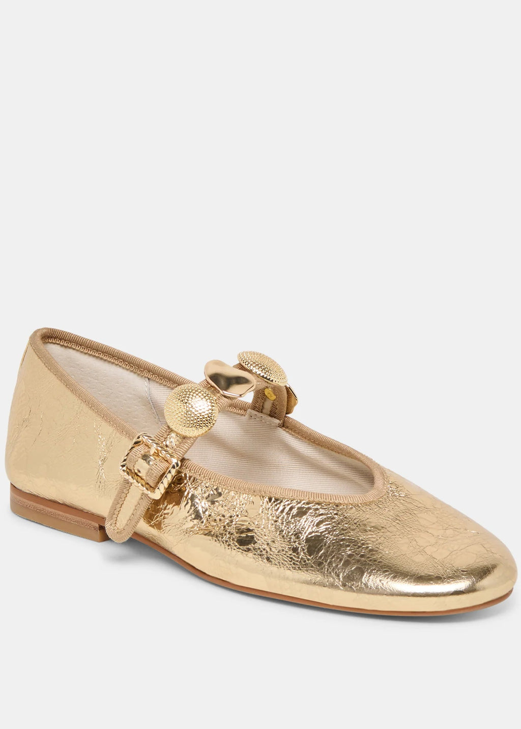 Gold flat shoe with a decorative strap on a light gray background