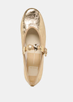 Gold flat shoe with decorative elements on a light gray background