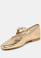 Gold flat shoe with a decorative strap on a white background