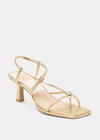 Gold high-heeled sandal on a light gray background