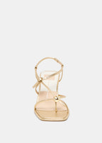 Gold high-heeled sandal on a light gray background