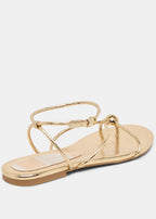 Gold sandal with thin straps on a white background