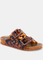 Tortoiseshell sandal with brown buckles on a light gray background