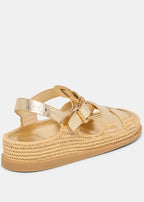 Gold sandal with woven sole on a light gray background