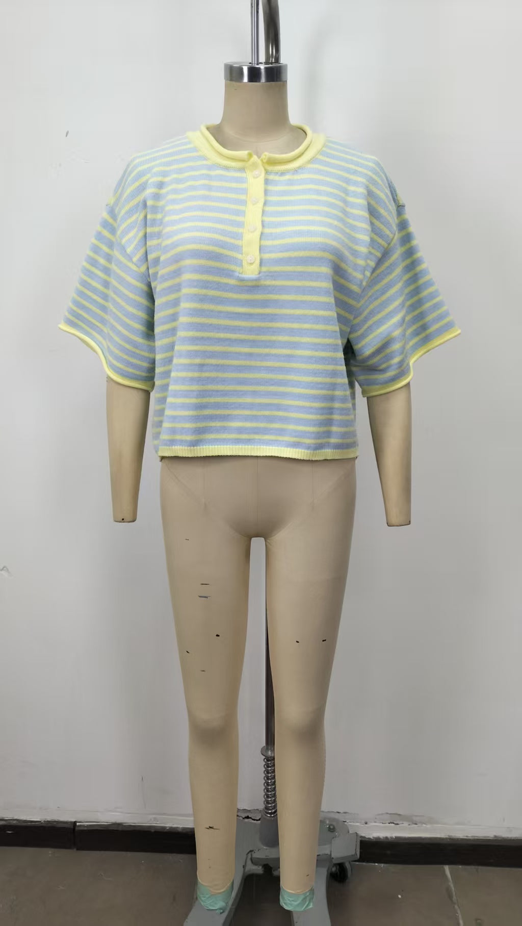 Mannequin wearing a striped shirt with yellow trim on a plain background