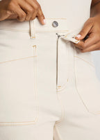 Person using a tool to open a zipper on light-colored pants.