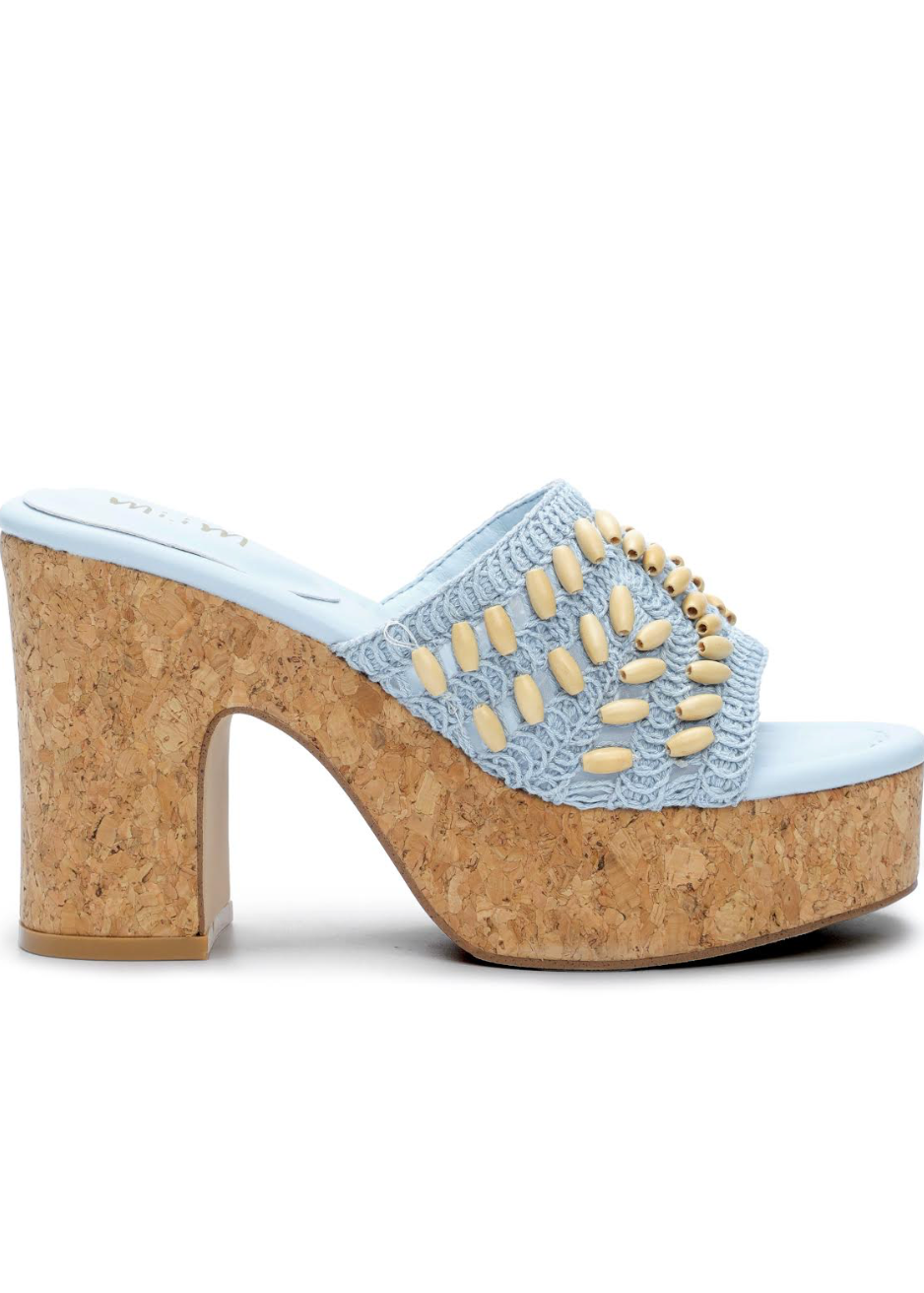 High-heeled shoe with cork sole and light blue lace uppers on a white background