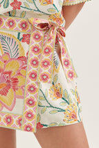 Close-up of a colorful floral dress with a tie waist on a white background