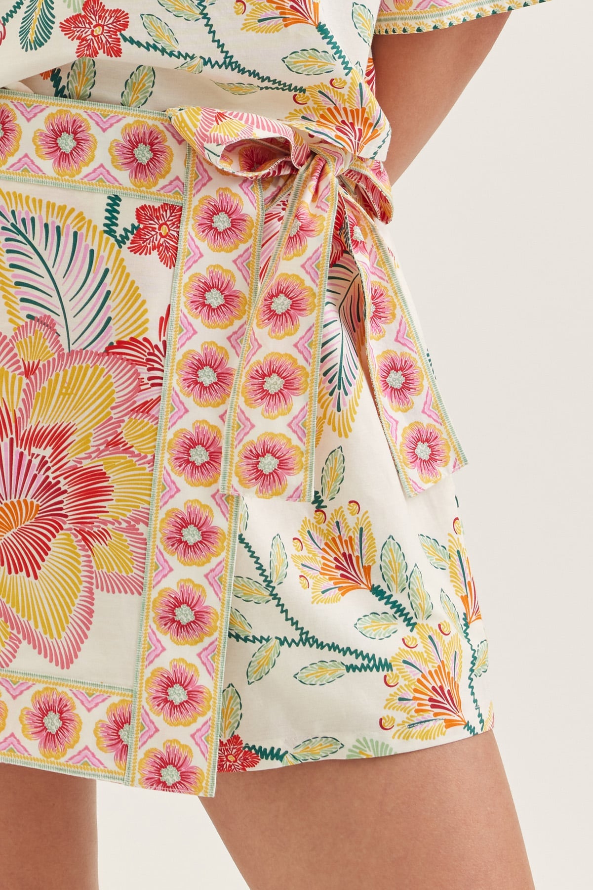 Close-up of a colorful floral dress with a tie waist on a white background