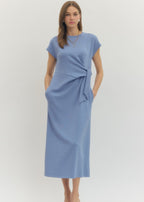 Woman wearing a blue dress with a tie waist on a white background