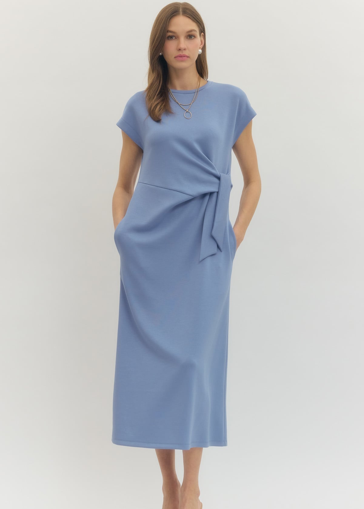 Woman wearing a blue dress with a tie waist on a white background