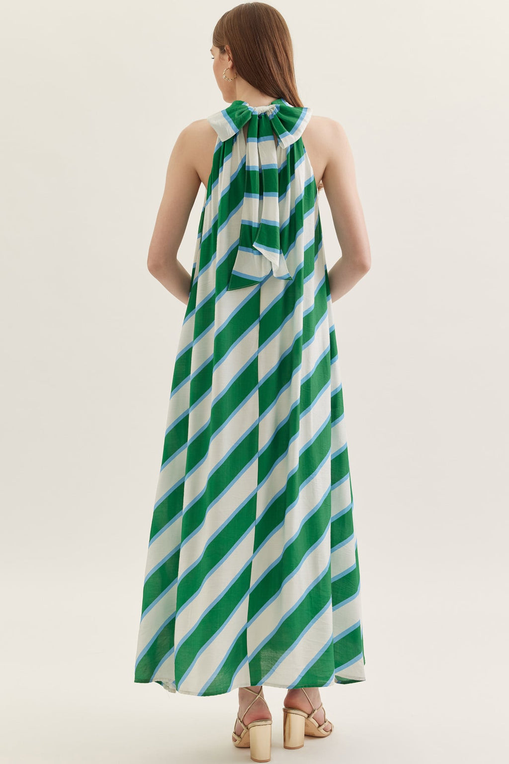 Woman wearing a green and white striped dress on a plain background