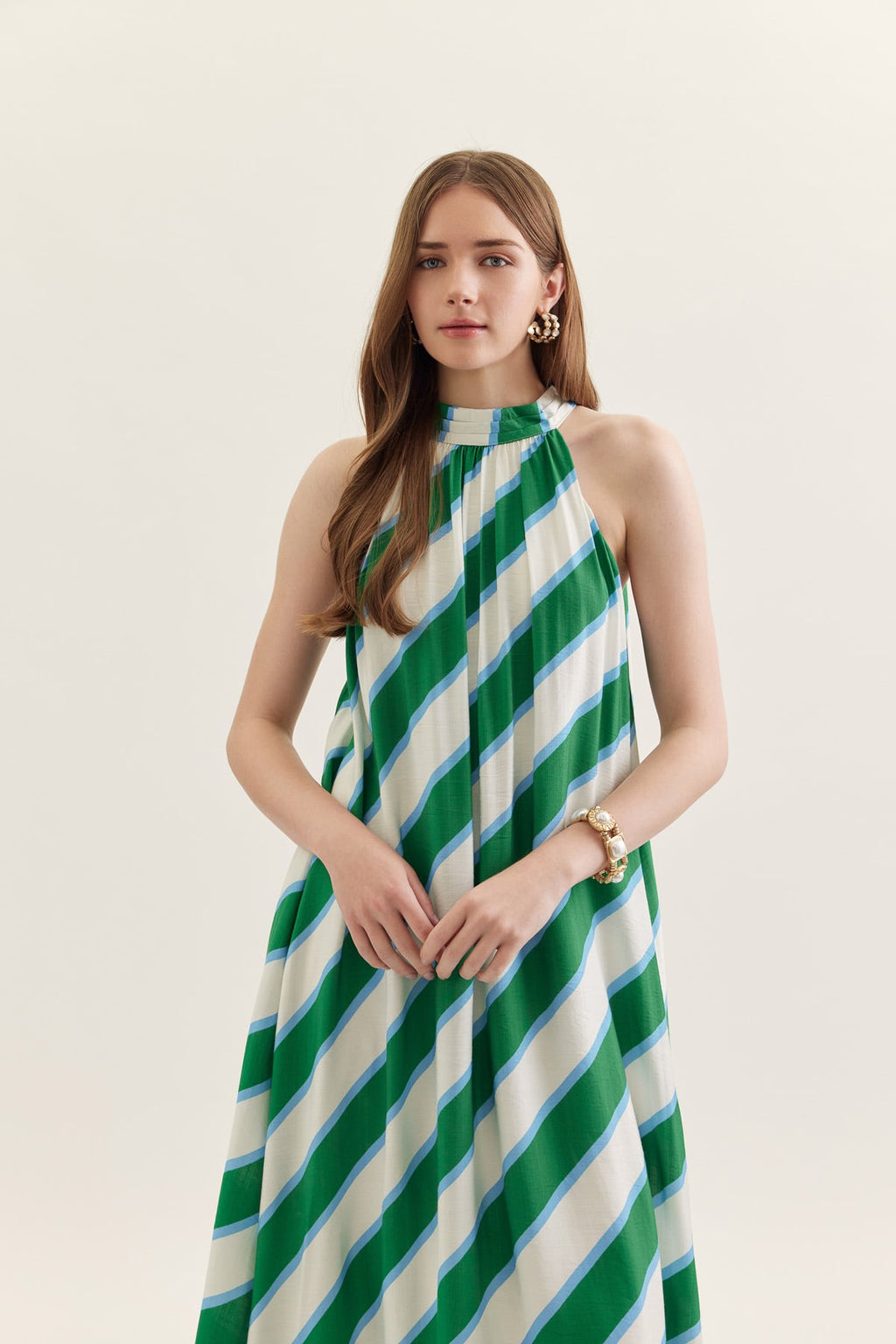 Woman wearing a green and white striped dress on a plain background