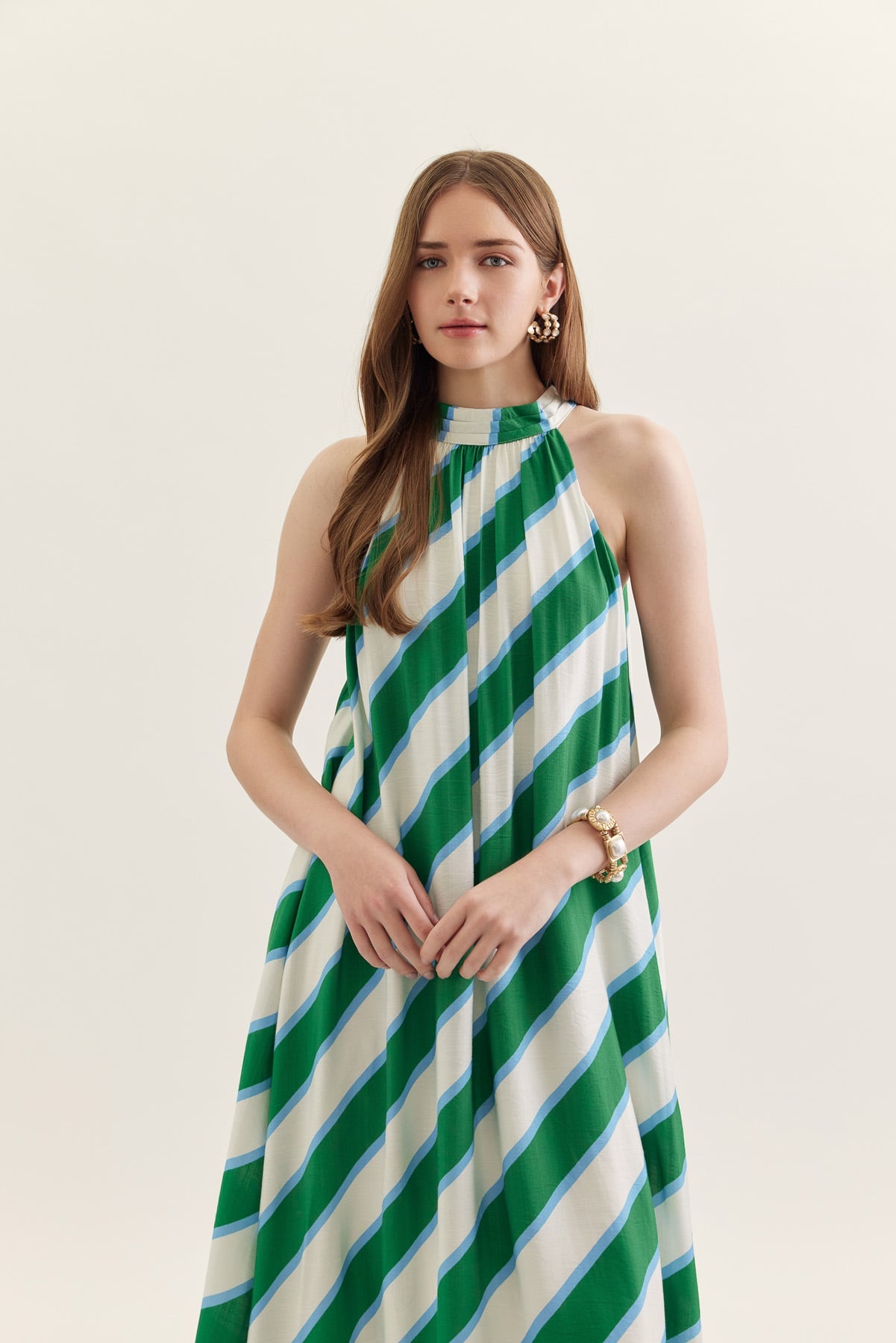Woman wearing a green and white striped dress on a plain background