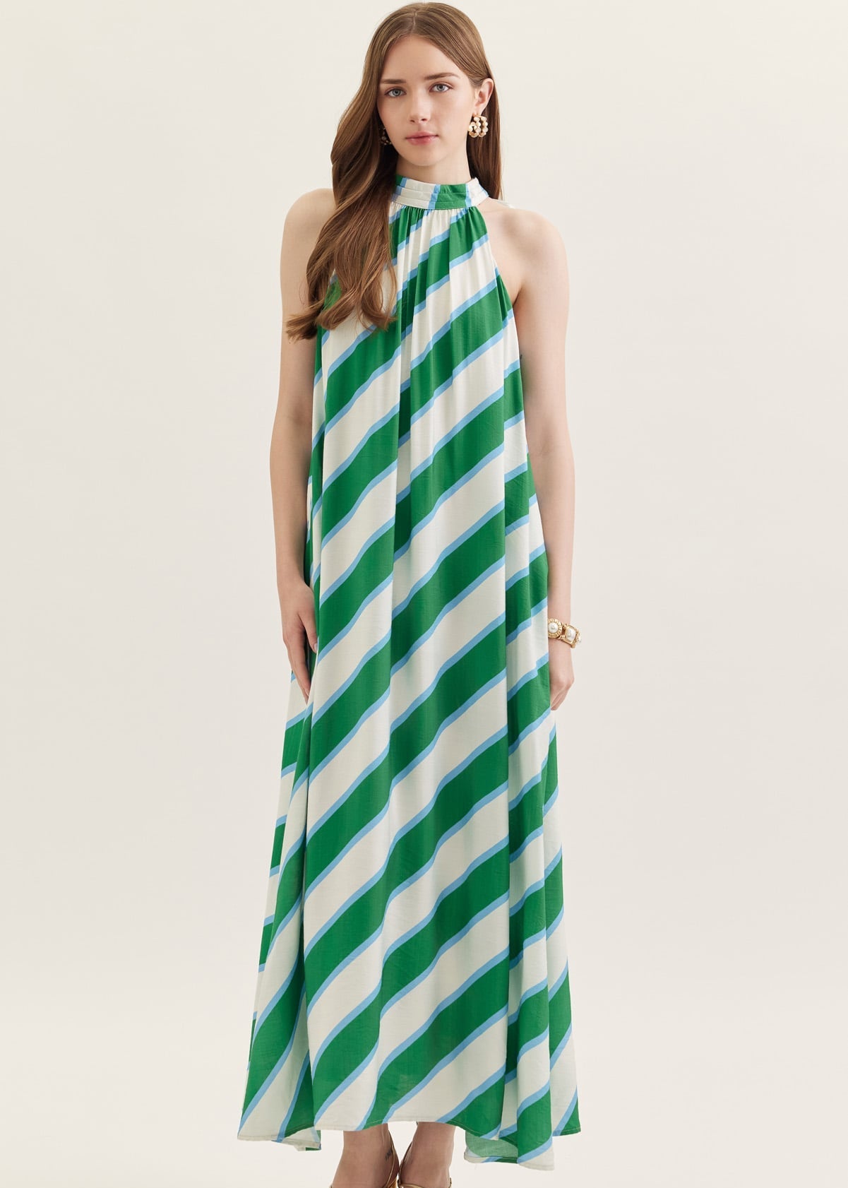 Woman wearing a green and white striped halter neck dress on a white background