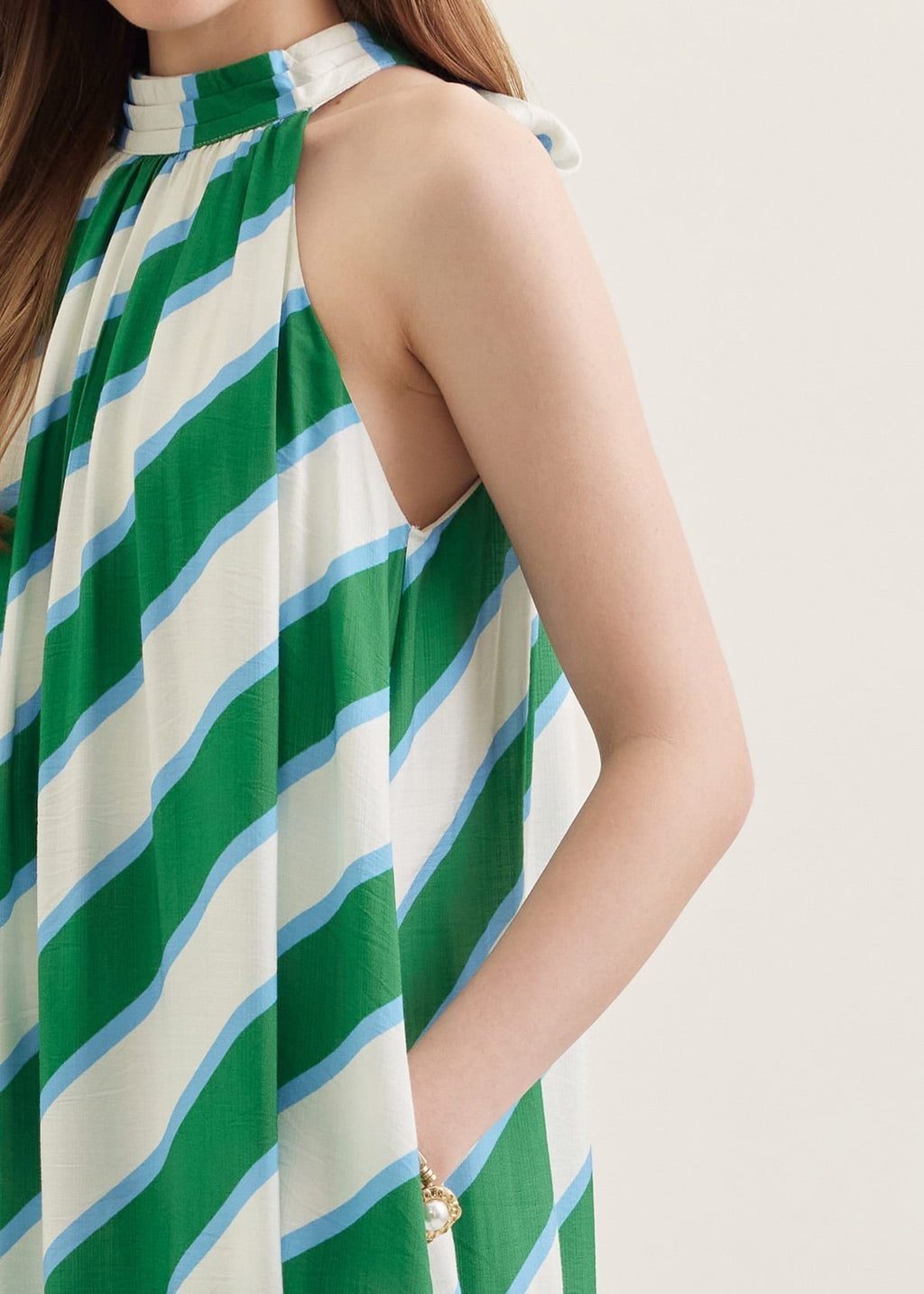 Green and white striped dress worn by a person on a plain background