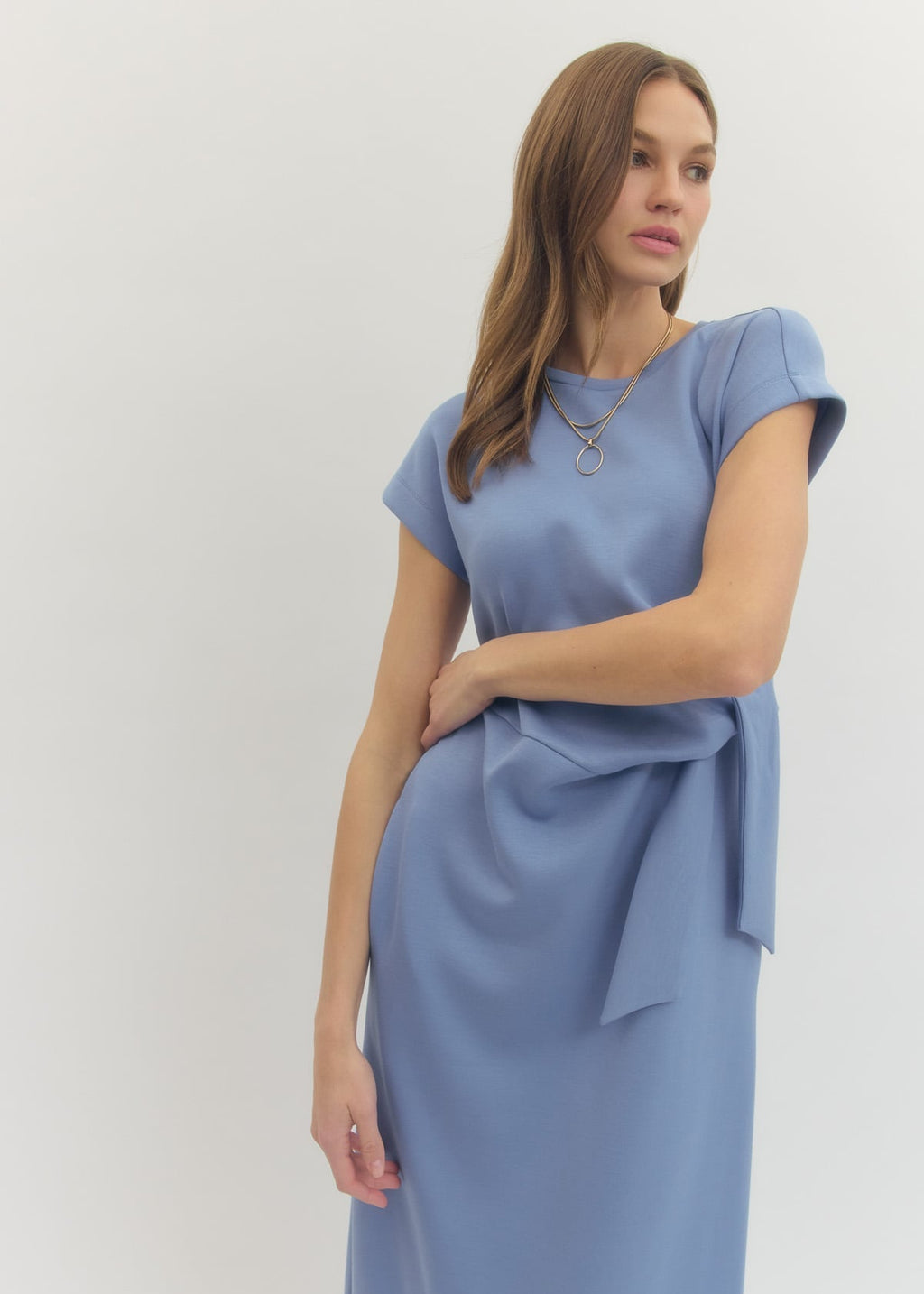 Woman wearing a light blue dress with a tie detail on a white background