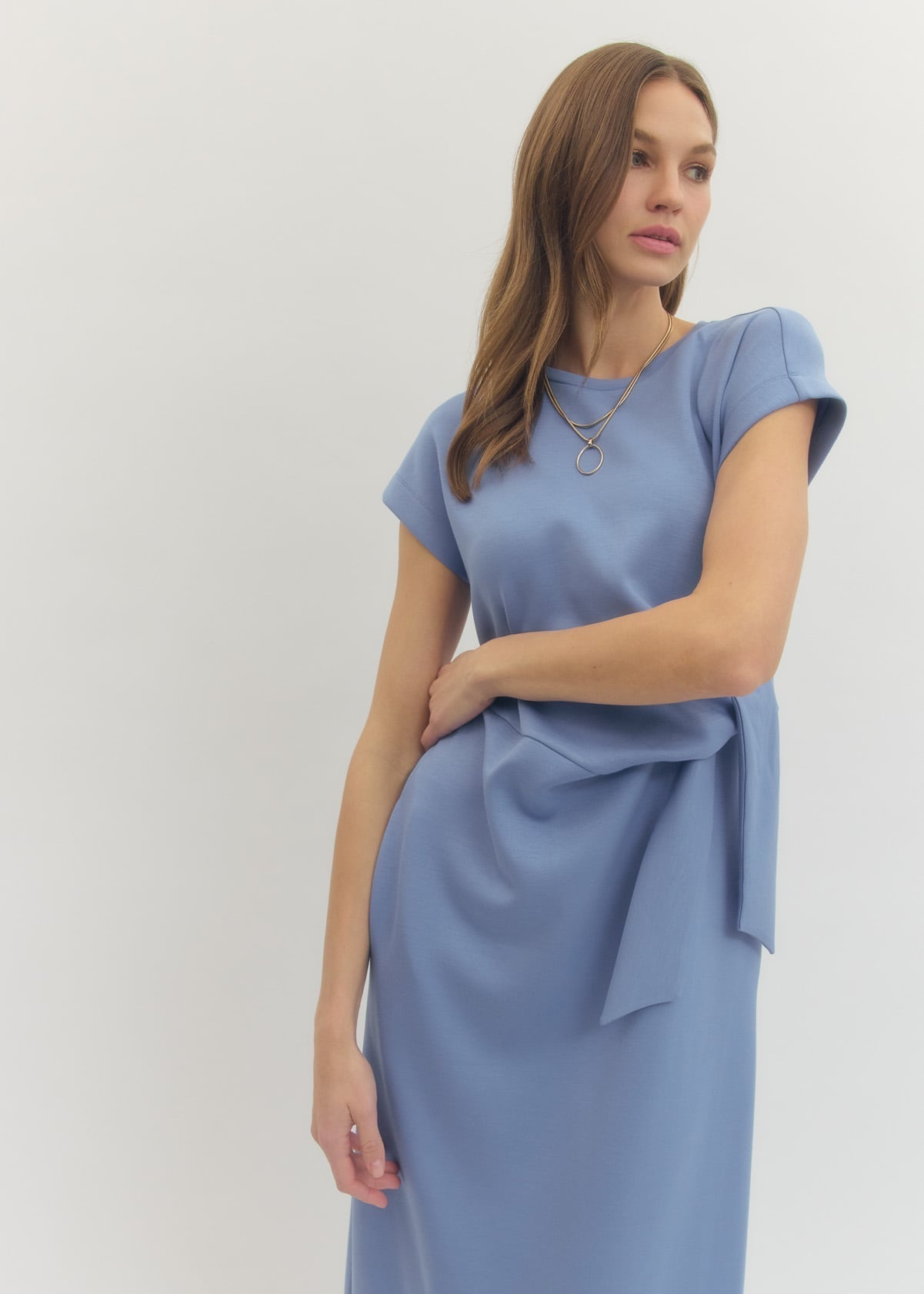 Woman wearing a light blue dress with a tie detail on a white background